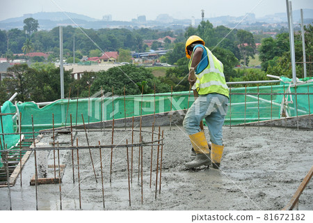 JASIN, MALAYSIA -NOVEMBER 13, 2015: Construction worker leveling wet concrete has been poured. They also use a vibrator machine in this work. JASIN, MALAYSIA -NOVEMBER 13, 2015: Construction worker leveling wet concrete has been poured. They also use a vibrator machine in this work. 81672182