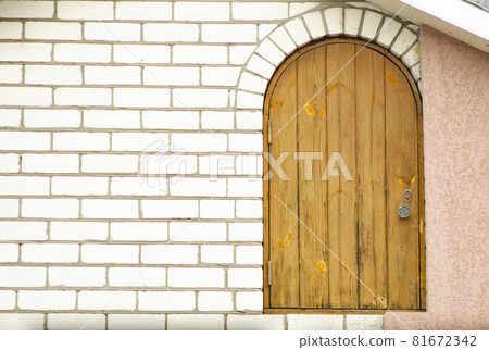 Arched wooden door with a semicircular top in a white brick wall Arched wooden door with a semicircular top in a white brick wall 81672342