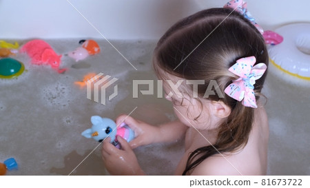 Little girl 3 years old with two ponytails on her head, bathes and washes in the water in the Little girl 3 years old with two ponytails on her head, bathes and washes in the water in the 81673722