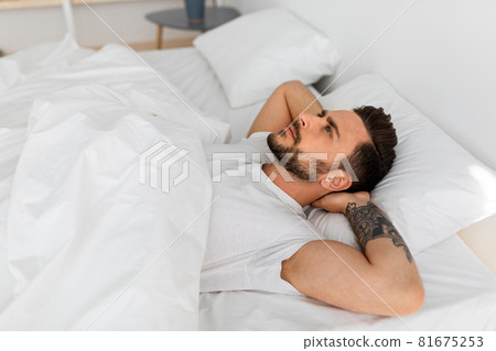 Thoughts in head not let fall asleep. Millennial man lying in bed and looking at ceiling, thinking of something 81675253