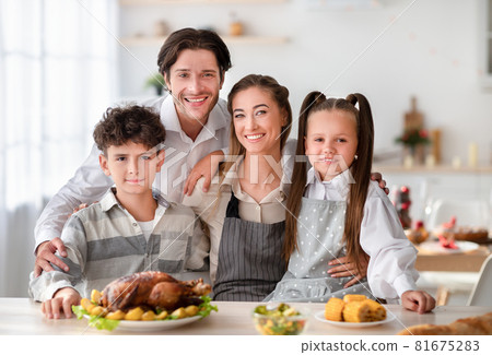 Young parents with son and daughter smiling at camera, cooking Thanksgiving or Christmas dinner with turkey at kitchen 81675283