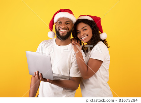 Online holiday shopping. Happy young african american family posing with laptop and smiling to camera, yellow background 81675284