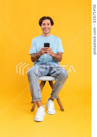 Happy guy using mobile phone at studio 81675456