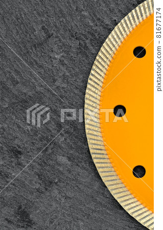Fragment of a yellow diamond cutting wheel on a dark gray granite background, the concept of stone processing in the interior and construction. Vertical image. 81677174