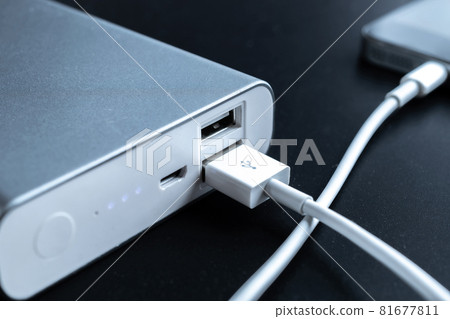 Phone power bank. Mobile phone or smartphone battery charging from portable powerbank with white usb cable. External battery for mobile devices. Phone power bank. Mobile phone or smartphone battery charging from portable powerbank with white usb cable. External battery for mobile devices. 81677811