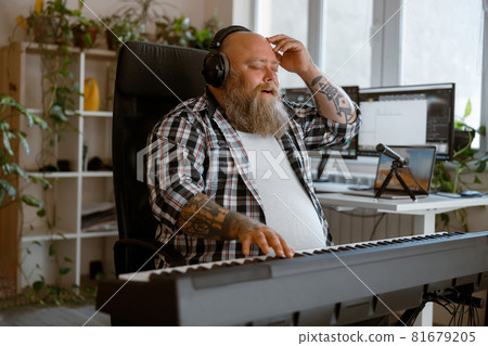 Inspired man composer with headphones writes music on synthesizer in home studio 81679205