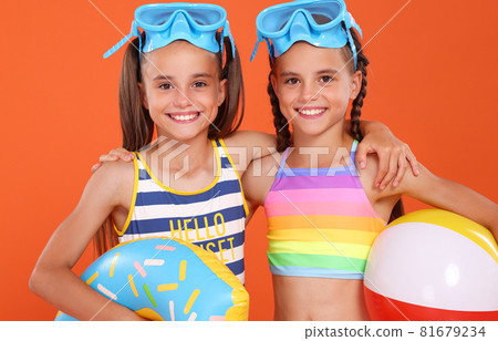 Smiling twin sisters with blue goggles embracing each other 81679234