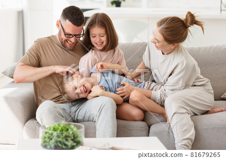 Happy beautiful family having fun and playing while relaxing on sofa in living room Happy beautiful family having fun and playing while relaxing on sofa in living room 81679265