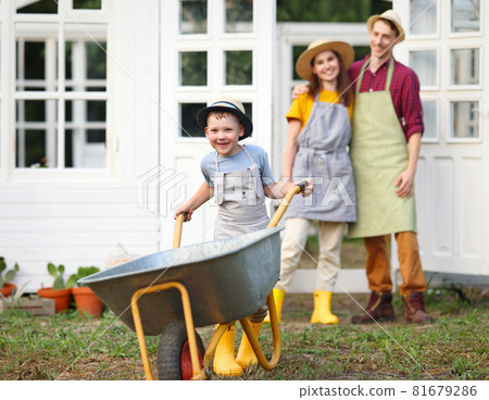Parents and kid standing near orangery in garden 81679286