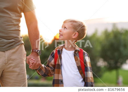 Schoolboy looking at dad with smile while going to first grade in school on sunny autumn day Schoolboy looking at dad with smile while going to first grade in school on sunny autumn day 81679656