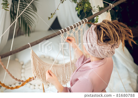 Woman with high hairstyle weaving macrame 81680788