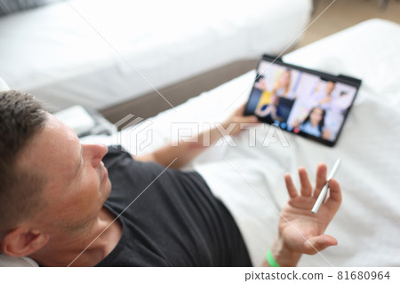 Man conducts an online team briefing while lying in bed Man conducts an online team briefing while lying in bed 81680964