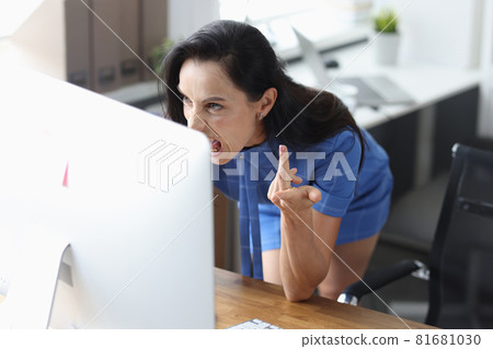 Young business woman sitting with laptop and screaming with angry expression closeup 81681030