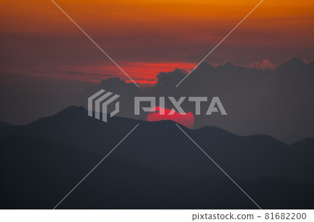 鮮紅的太陽從山巒和雲層的縫隙中升起 81682200