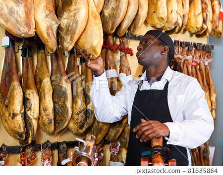 Serious shop owner checking quality of jamon 81685864