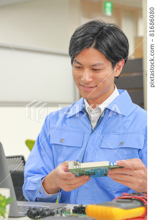 Electrical engineer holding the board and looking at the PC screen 1 Electrical engineer holding the board and looking at the PC screen 1 81686080