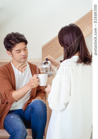 年輕的亞洲女人和亞裔男人手裡拿著一杯咖啡正在享受在家共度時光。 81686300