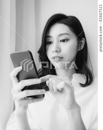 Young Asian woman using smartphone at home 81687521