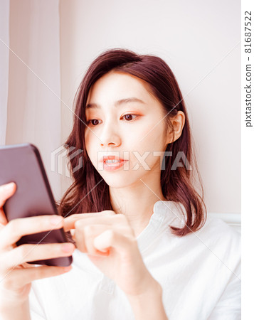 年輕的亞洲女性在家裡使用智慧型手機 年輕的亞洲女性在家裡使用智慧型手機 81687522