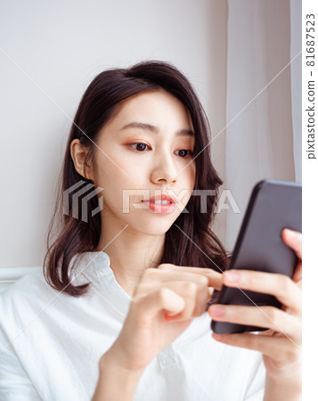 年輕的亞洲女性在家裡使用智慧型手機 年輕的亞洲女性在家裡使用智慧型手機 81687523