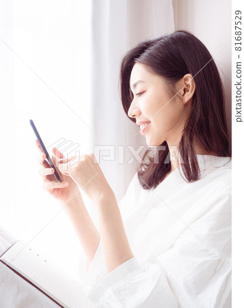 Young Asian woman using smartphone at home Young Asian woman using smartphone at home 81687529