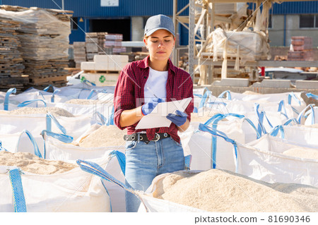 Female supervisor checking quality of building mix at store 81690346