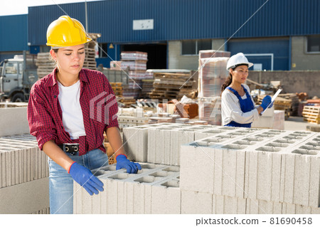 Woman checking quality of bricks at construction store 81690458