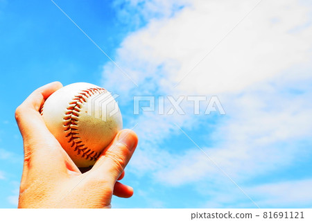 A hand holding a baseball and lifting it up under the blue sky A hand holding a baseball and lifting it up under the blue sky 81691121
