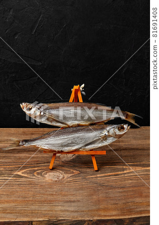 Two air-dried sabrefish on serving stand on black background Two air-dried sabrefish on serving stand on black background 81691408