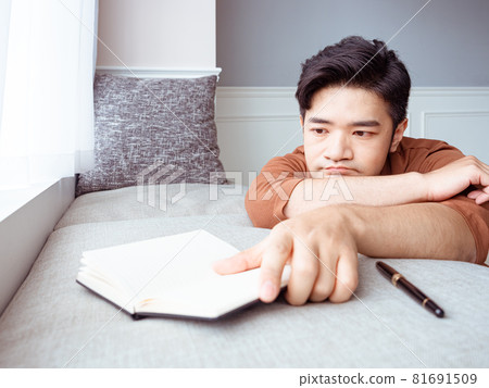 Young Asian man reading book while relaxing at home Young Asian man reading book while relaxing at home 81691509