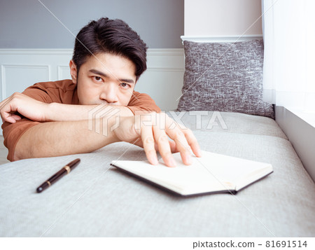 Young Asian man reading book while relaxing at home Young Asian man reading book while relaxing at home 81691514