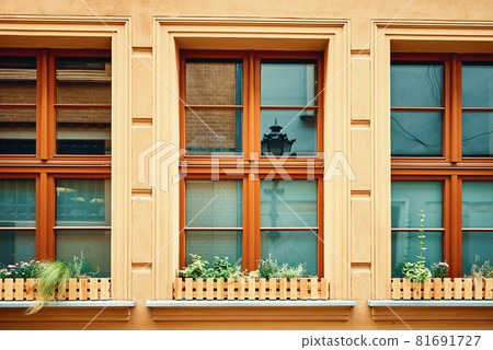 Vintage building facade with windows and flowers on windowsill 81691727