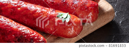 Sausages panorama. A close-up of tasty grilled sausages on a wooden board Sausages panorama. A close-up of tasty grilled sausages on a wooden board 81691833