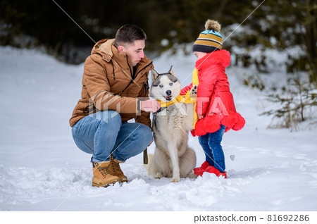 Happy father and little daughter and husky dog in winter forest walking in winter. Happy father and little daughter and husky dog in winter forest walking in winter. 81692286