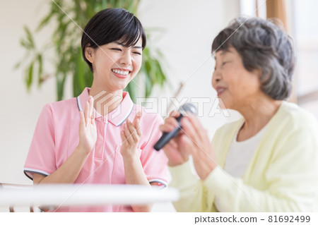 Nursing care scene Recreation Karaoke Senior women and caregivers singing enthusiastically with a microphone 81692499