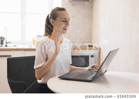Young woman working on laptop at kitchen. Female freelancer working online Young woman working on laptop at kitchen. Female freelancer working online 81693309