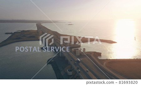 Aerial view of a truck with POSTAL SERVICE infographics driving along the road across the sea Aerial view of a truck with POSTAL SERVICE infographics driving along the road across the sea 81693820