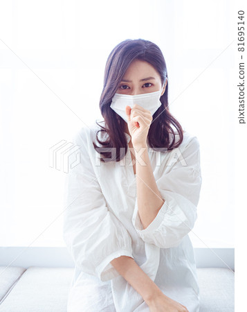 Young Asian woman suffering from flu wearing surgical mask at home Young Asian woman suffering from flu wearing surgical mask at home 81695140