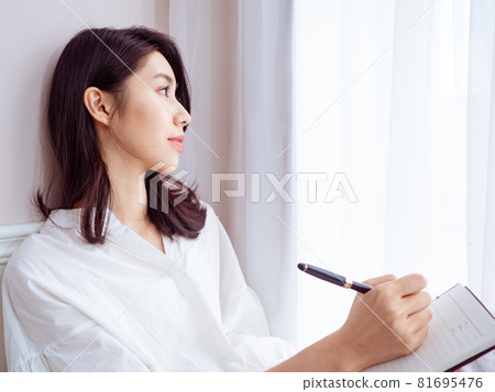 一位美麗的亞洲年輕女性在書中寫下一些東西 一位美麗的亞洲年輕女性在書中寫下一些東西 81695476