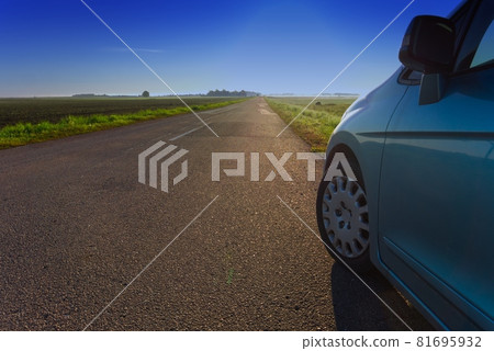 Car parked at the edge of an empty country road 81695932