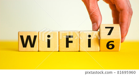WiFi 6 or 7 symbol. Businessman turns a wooden cube and changes the words WiFi 6 to WiFi 7. Beautiful yellow, white background, copy space. Business, technology and WiFi 6 to WiFi 7 concept. WiFi 6 or 7 symbol. Businessman turns a wooden cube and changes the words WiFi 6 to WiFi 7. Beautiful yellow, white background, copy space. Business, technology and WiFi 6 to WiFi 7 concept. 81695960