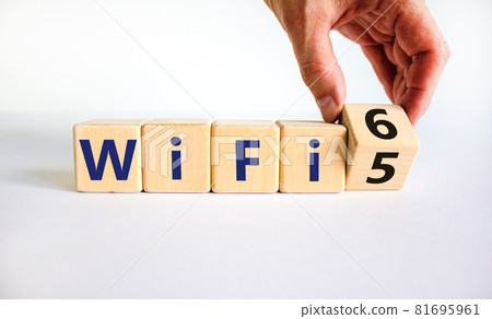 WiFi 5 or 6 symbol. Businessman turns a wooden cube and changes the words WiFi 5 to WiFi 6. Beautiful white background, copy space. Business, technology and WiFi 5 to WiFi 6 concept. WiFi 5 or 6 symbol. Businessman turns a wooden cube and changes the words WiFi 5 to WiFi 6. Beautiful white background, copy space. Business, technology and WiFi 5 to WiFi 6 concept. 81695961