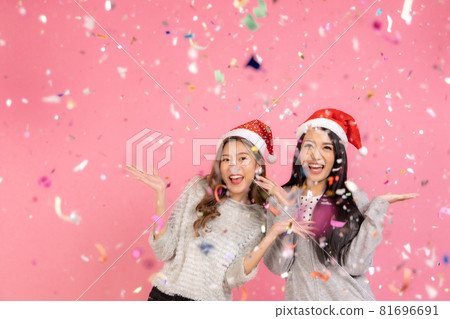 Portrait of two lovely cute asian women in christmas hats  looking at camera isolated over pink background.Attractive asian woman smile in christmas, new year, valentine day, birthday celebration 81696691