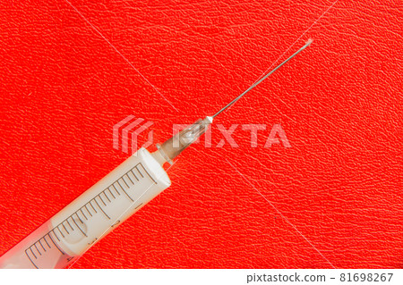 A syringe or injection with medicine or drugs lies on a red background. Addiction concept 81698267