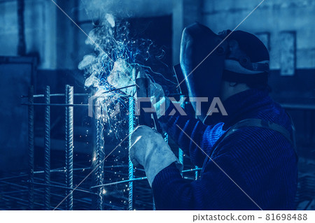 Working man is doing welding work on metal structures in a factory or industrial enterprise 81698488