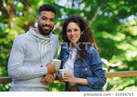 Happy couple resting and looking at camera outdoors in a tree house, weekend away and digital detox concept. 81698765