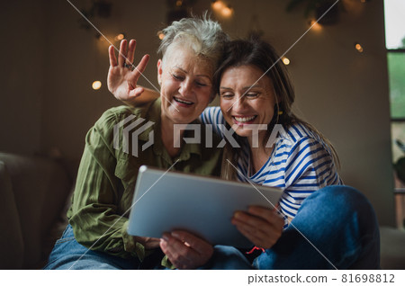 Portrait of happy senior mother with adult daughter indoors at home, using tablet. Portrait of happy senior mother with adult daughter indoors at home, using tablet. 81698812