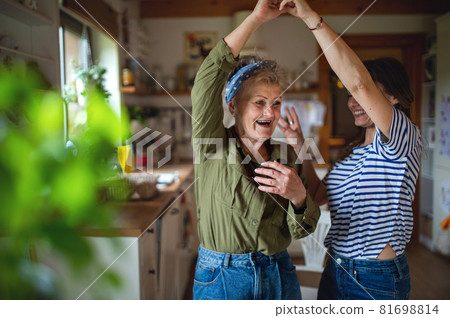 Happy senior mother having fun with adult daughter indoors at home, dancing. Happy senior mother having fun with adult daughter indoors at home, dancing. 81698814