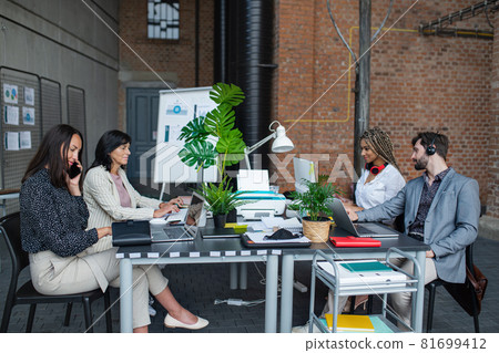 Young and old businesspeople sitting and working at desk in office, cooperation and coworking concept. 81699412