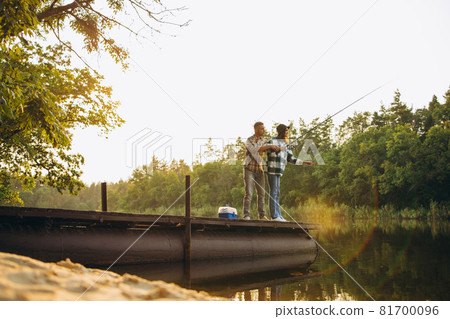 Portrait of young couple fishing on warm summer day in countryside at sunrise Portrait of young couple fishing on warm summer day in countryside at sunrise 81700096